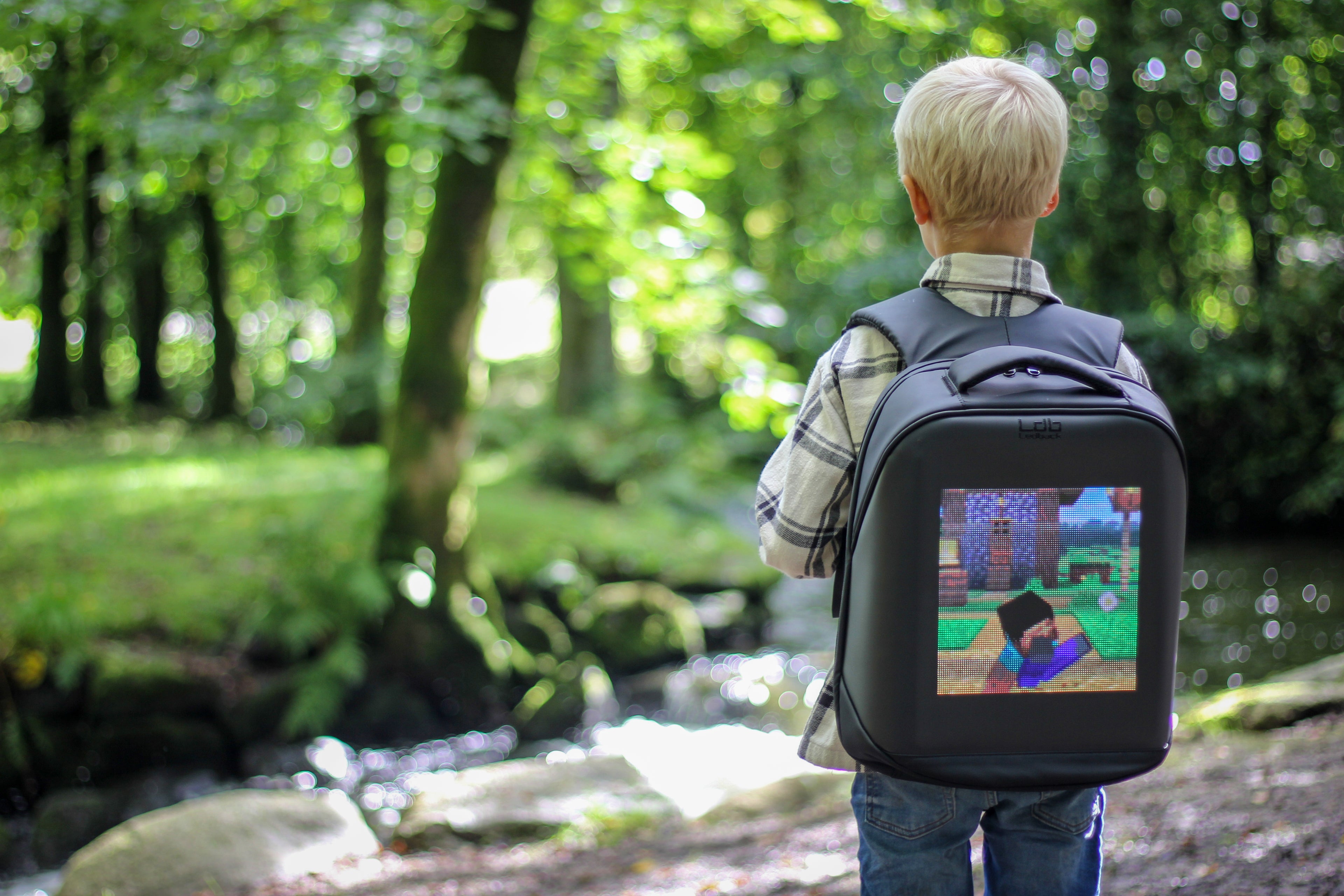 Boy in the park overlooking a stream, wearing a Ledback HD backpack displaying a Minecraft picture on a large high resolution LED screen.